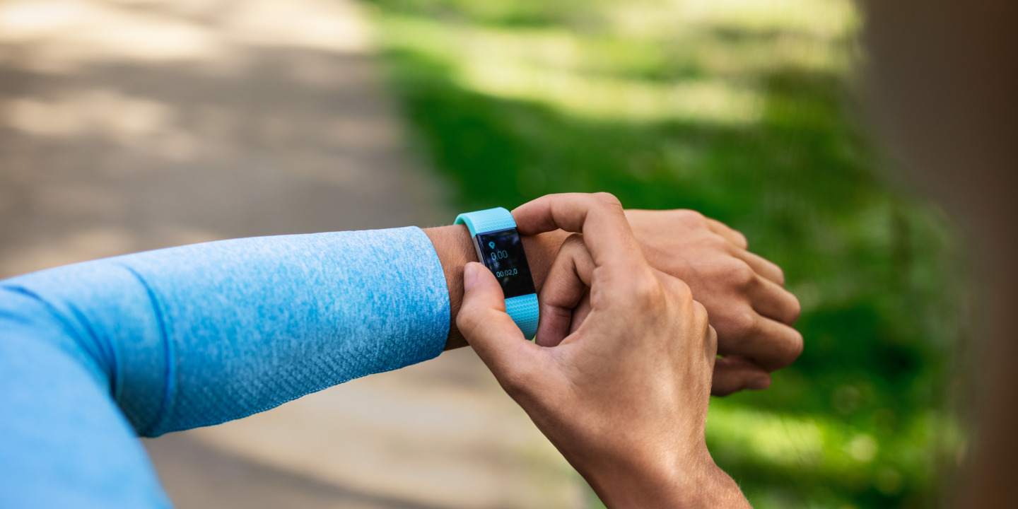 Läuferin im blauen Shirt checkt Smartwatch