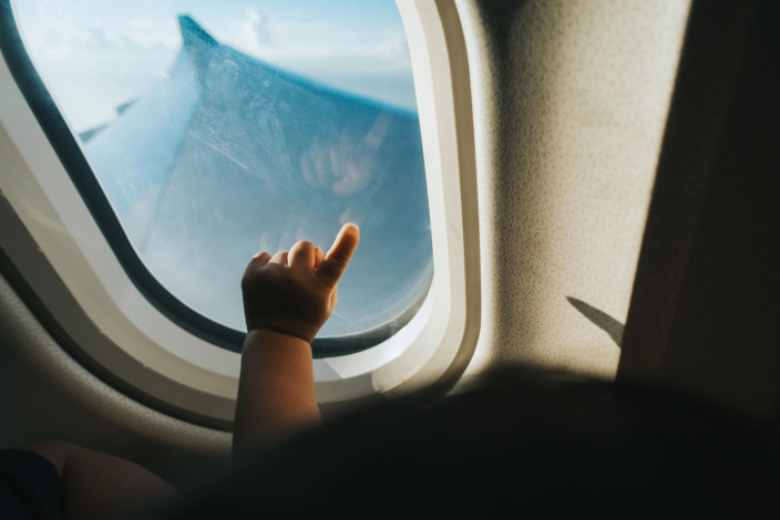 Die Hand eines Babys vor einem Flugzeugfenster