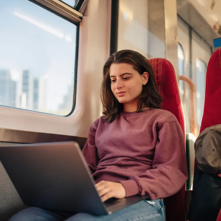 Frau, die im Zug am Laptop arbeitet