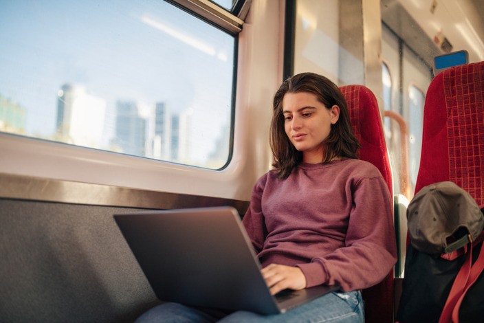 Frau, die im Zug am Laptop arbeitet