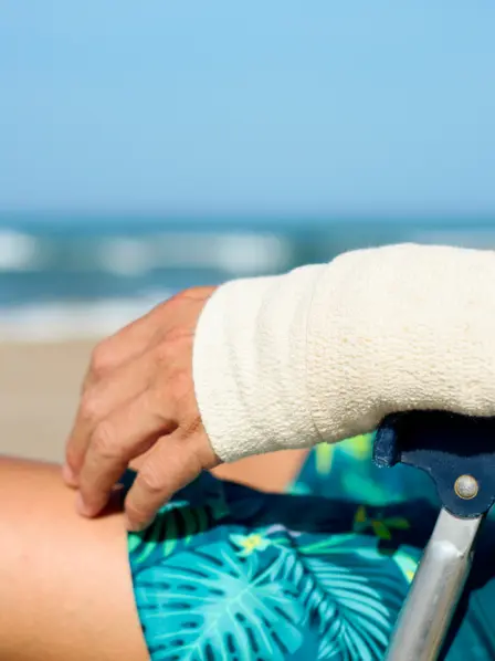 Person mit Bandage an der Hand am Strand