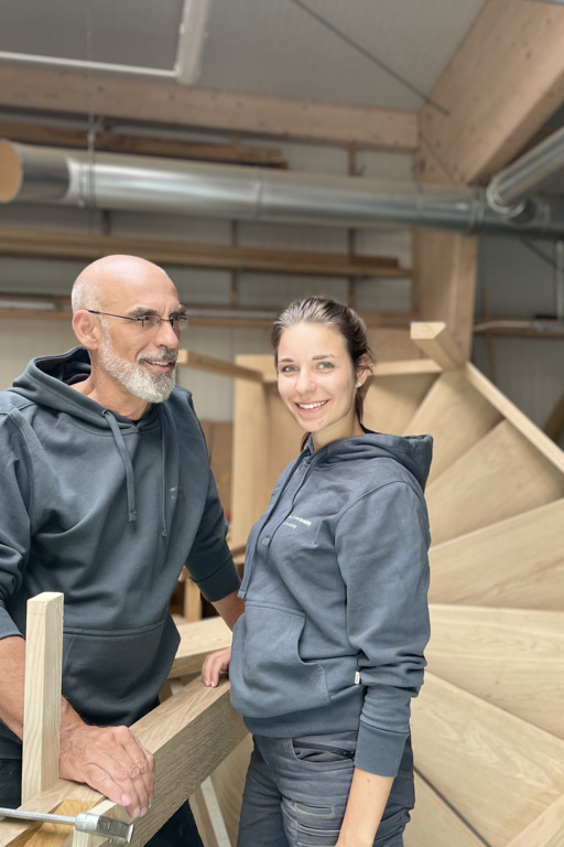 Ein Vater steht mit seiner Tochter in einem Handwerksbetrieb