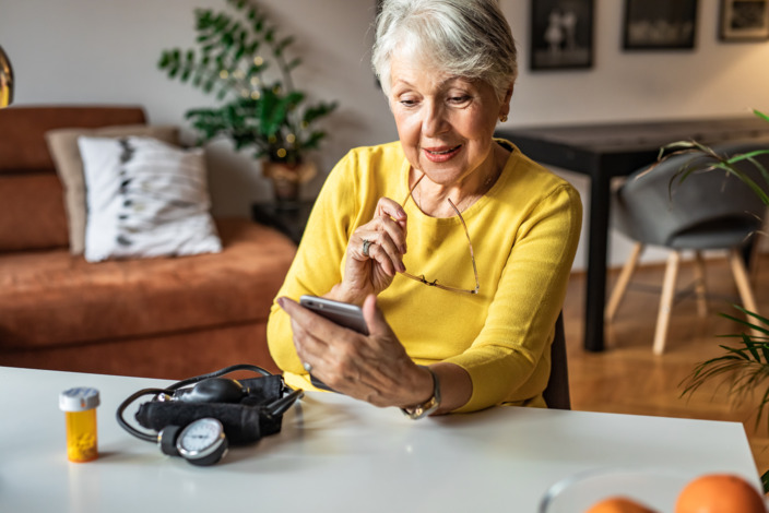 Ältere Dame, die auf ihr Smartphone schaut. 