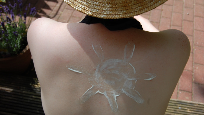 Nahaufnahme von Rücken mit einer Sonne aus Sonnencreme drauf. 
