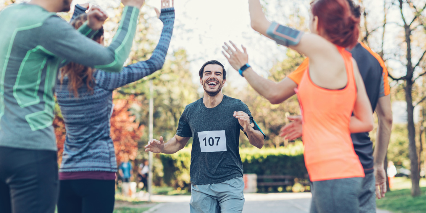 Jogger läuft durch klatschende Läufergruppe ins Ziel