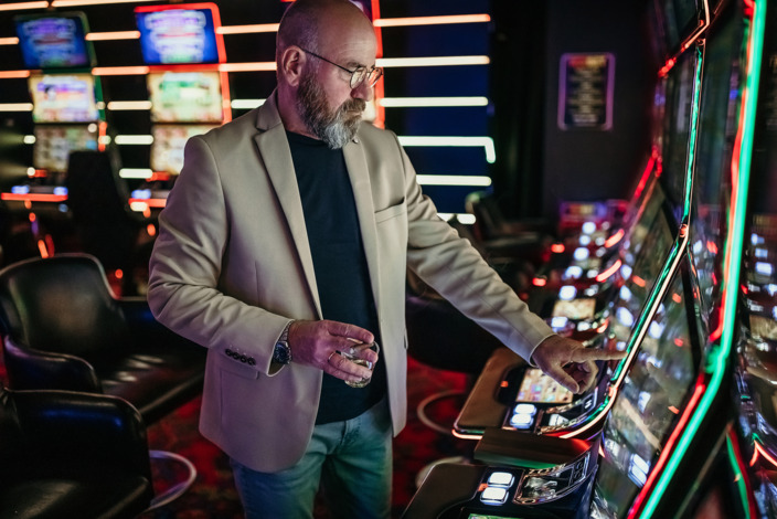 Mann steht am Spielautomat in der Spielhalle