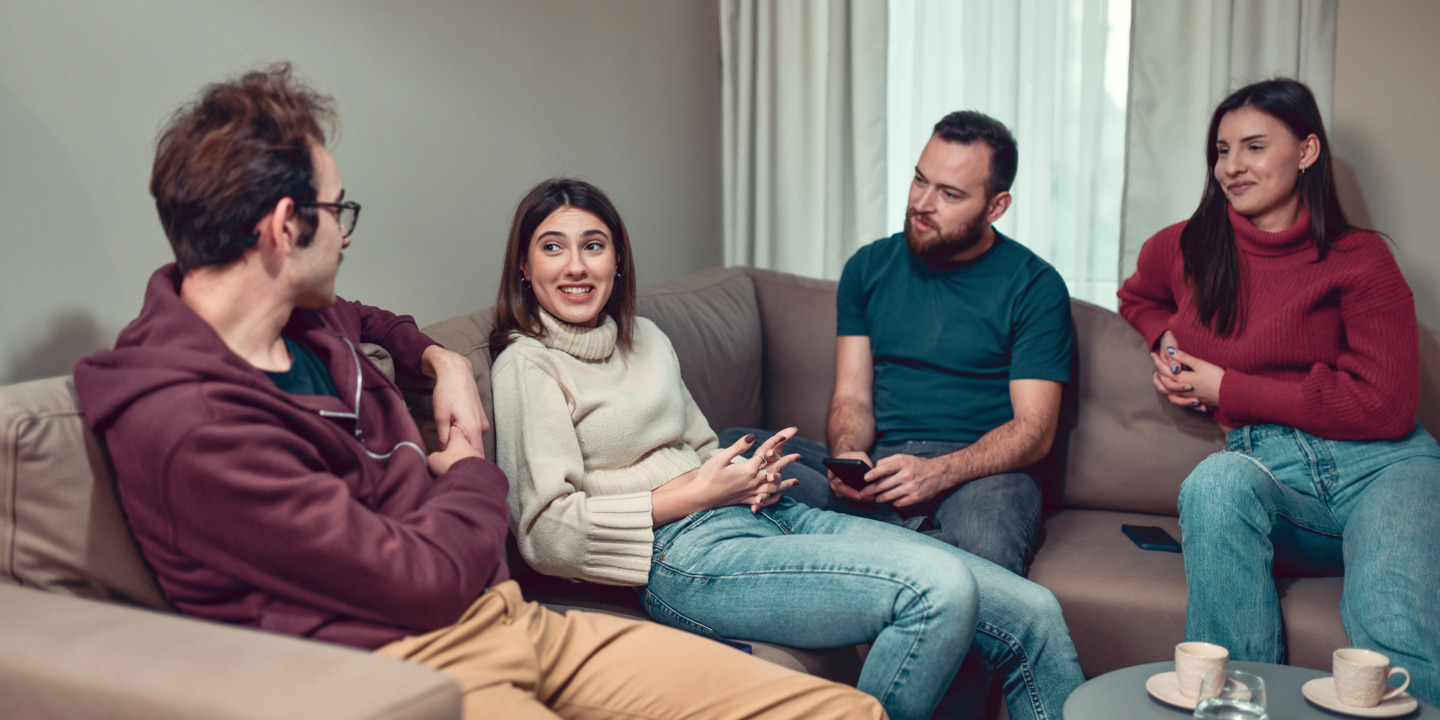 Zwei Frauen und zwei Männer sitzen auf einem Sofa und unterhalten sich.