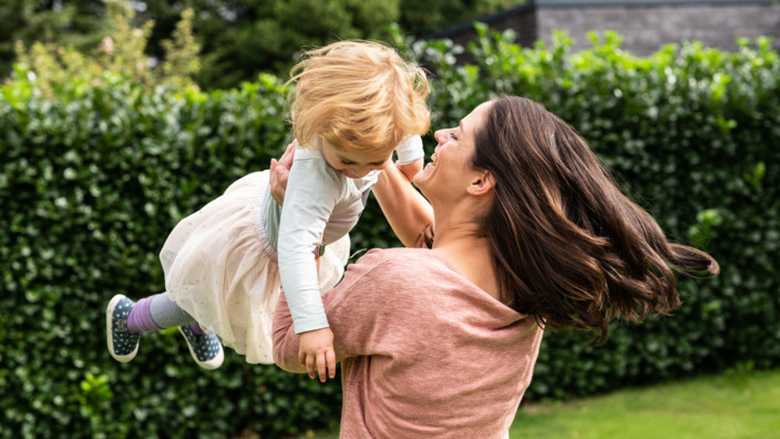 Mutter tollt mit ihrer kleinen Tochter durch den Garten