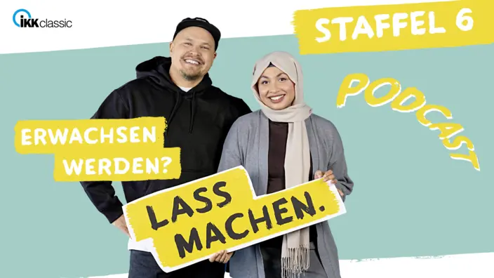 Urooba und Marco stehen gemeinsam vor einer grauen Wand. 