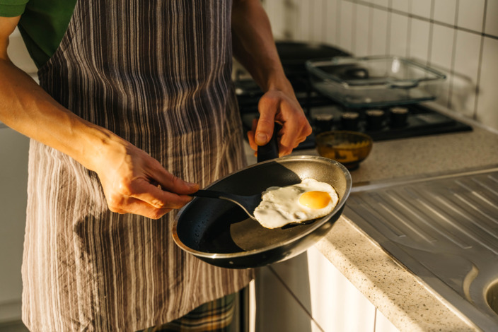 Eine Frau brät ein Spiegelei in einer Teflon-Pfanne