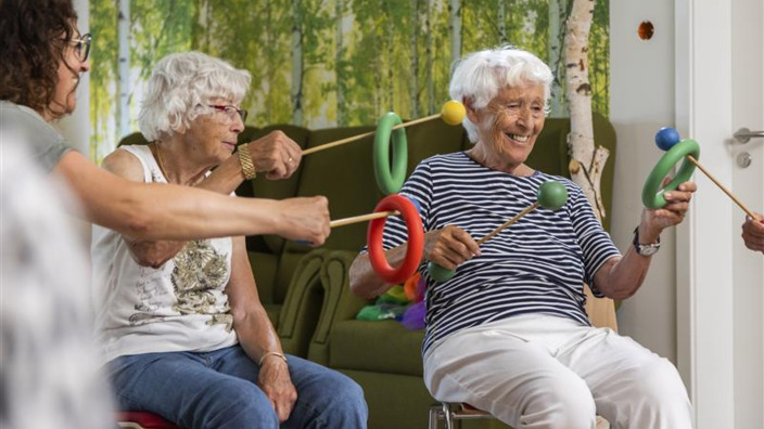 Ältere Frauen sitzen zusammen und machen ein Geschicklichkeitsspiel mit Ringen