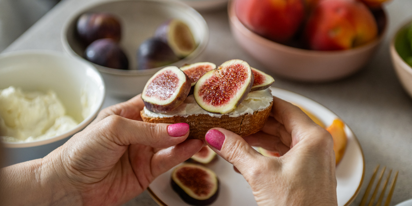 Zwei Hände halten ein mit Feigen belegtes Brot