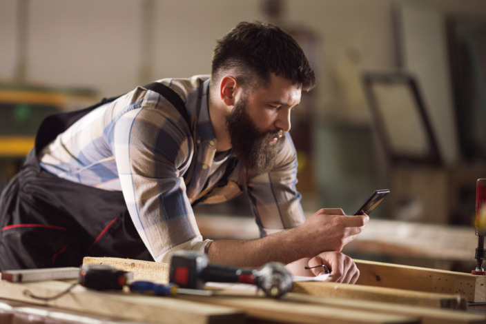 Ein Handwerker schaut auf sein Smartphone