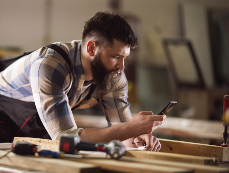 Ein Handwerker schaut auf sein Smartphone