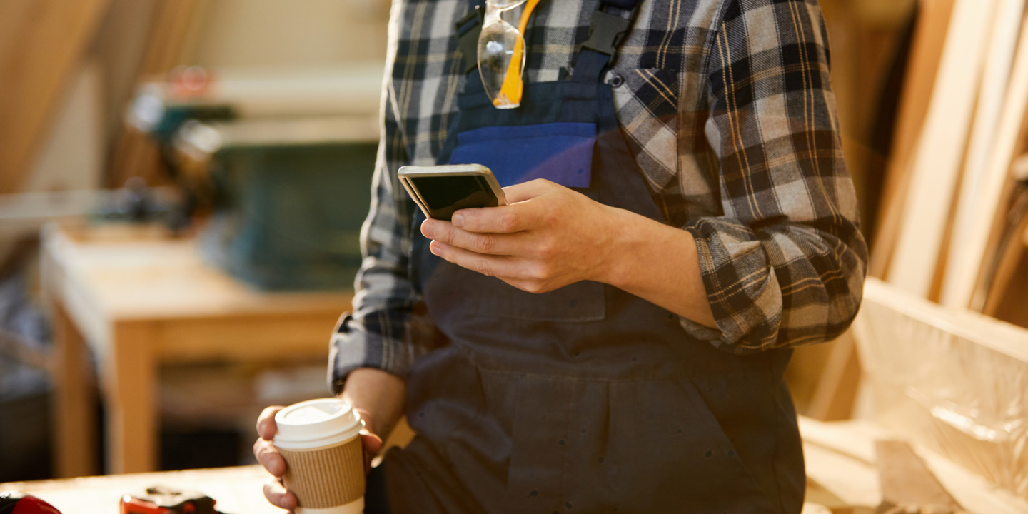 Handwerker schaut auf sein Smartphone.