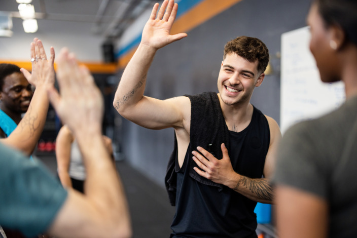 Junger Mann hebt die Hand zum High Five in einer Gruppe von Menschen