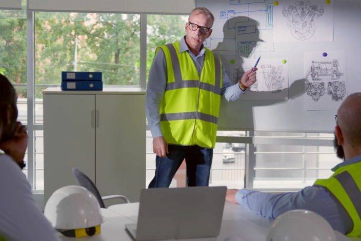 Mann leitet Workshop in einem Büro mit Mitarbeitenden.