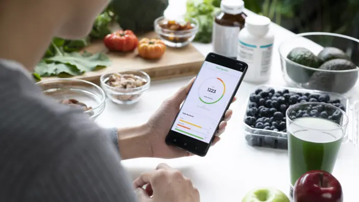 Mann berechnet auf seinem Smartphone seine Kalorienzufuhr