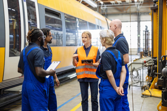 Eine Gruppe von Handwerkenden steht im Kreis und bespricht etwas