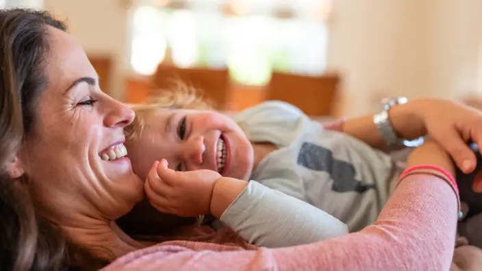 Mutter und Kind kuscheln lächelnd zusammen.