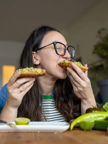 Eine Frau beißt genüsslich in ein Avocadobrot.
