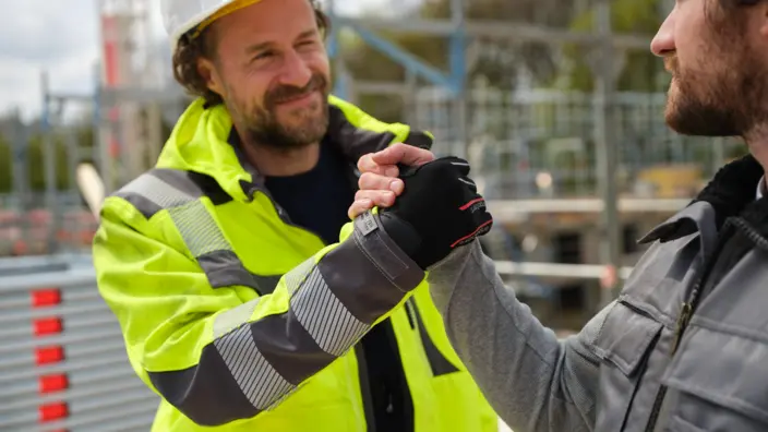 Zwei Bauarbeiter machen einen Handschlag. 