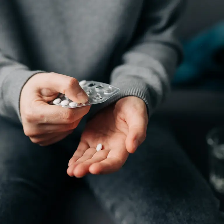 Mann nimmt sich Tabletten aus dem Blister heraus.