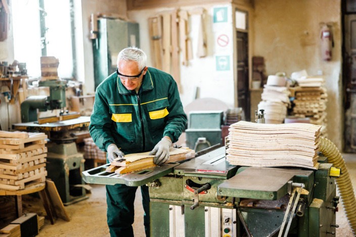 Ein älterer Handwerker zersägt Holz.