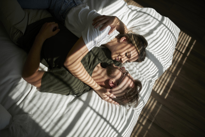 Ein Paar liegt im Bett und kuschelt miteinander.