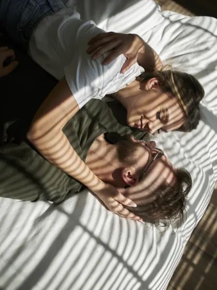 Ein Paar liegt im Bett und kuschelt miteinander.