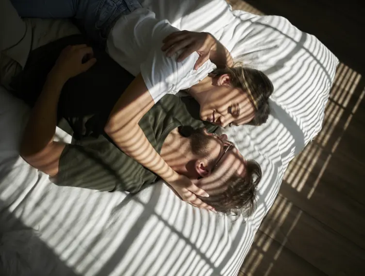 Ein Paar liegt im Bett und kuschelt miteinander.