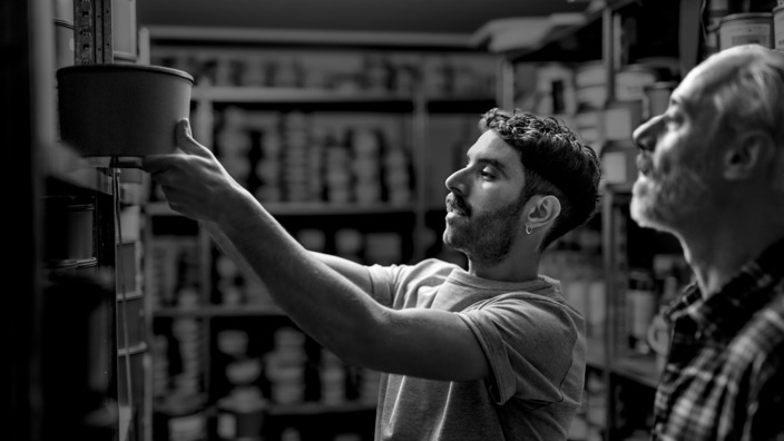 Zwei Männer in einer Druckerei stehen vor einem Regal. 