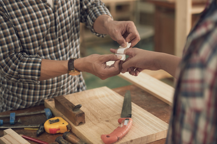 Ein Handwerker versorgt die Wunde seines Kollegen.