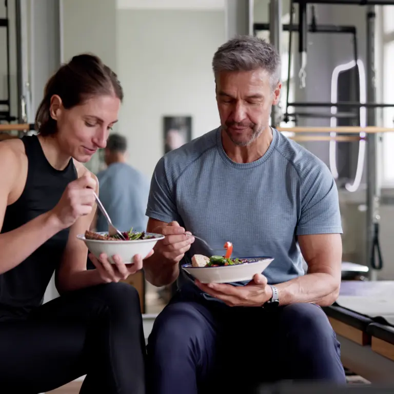 Frau und Mann in Trainingskleidung essen gesund.