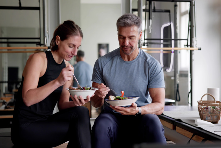 Ein Mann und eine Frau sitzen gemeinsam in Sportkleidung und essen.