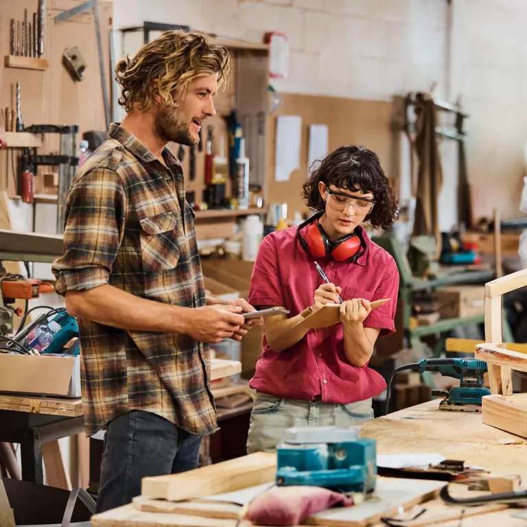 Ein Team von Handwerkern steht in einer Werkstatt und berät sich. 