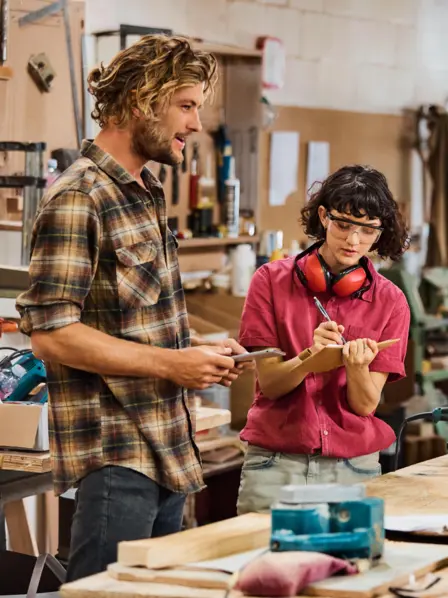 Ein Team von Handwerkern steht in einer Werkstatt und berät sich. 