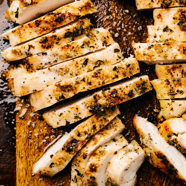  Kräuterhähnchen mit Zitronen-Knoblauch-Marinade auf einem Holz-Schneidebrett.