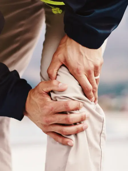 Mann hält sich das Knie.