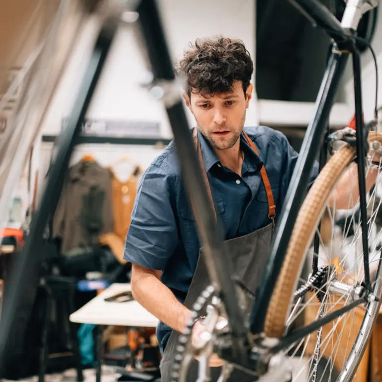 Mann steht in der Werkstatt und repariert ein Fahrrad.