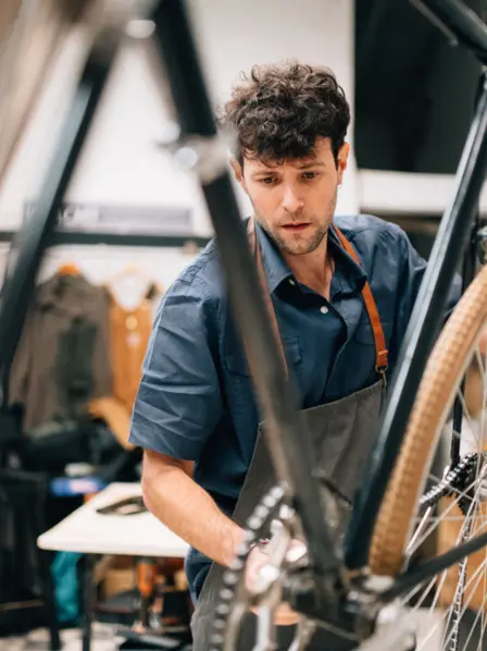 Mann steht in der Werkstatt und repariert ein Fahrrad.