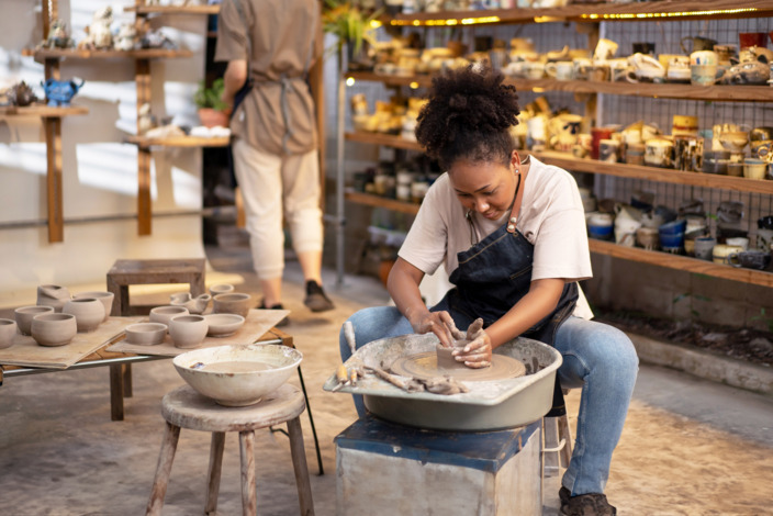 Eine junge Frau töpfert in einem Studio.