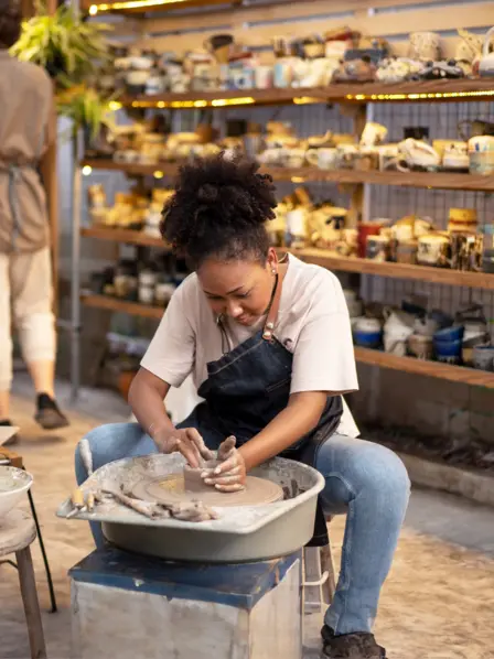 Eine junge Frau töpfert in einem Studio.
