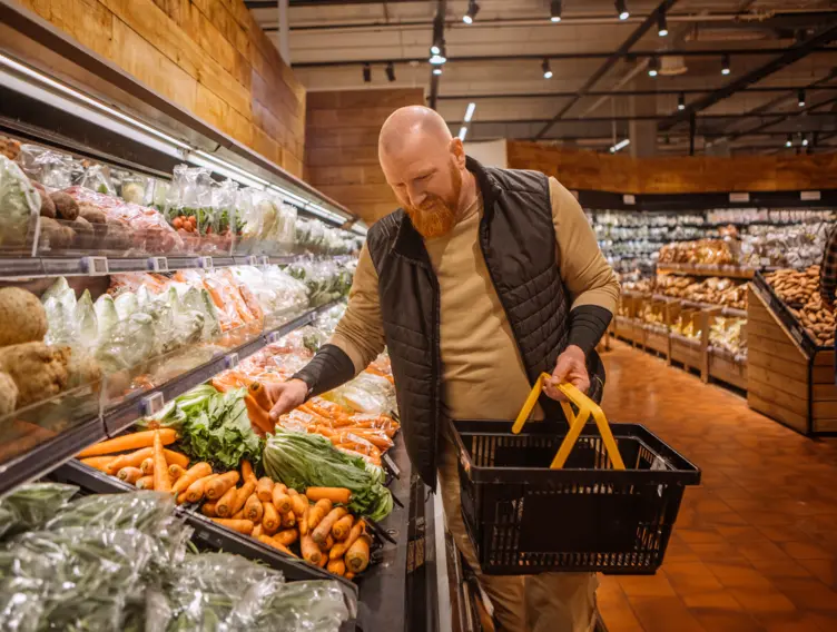 Mann kauft in der Gemüseabteilung im Supermarkt ein.