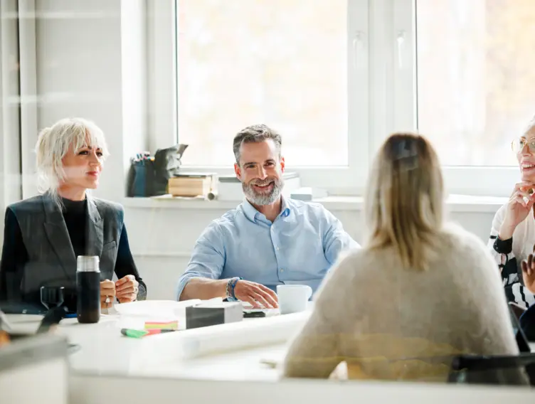 Zwei Männer und drei Frauen bilden den Betriebsrat und sitzen gemeinsam im Büro.