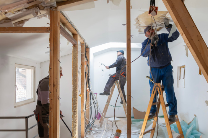 Drei Handwerker renovieren ein Zimmer.