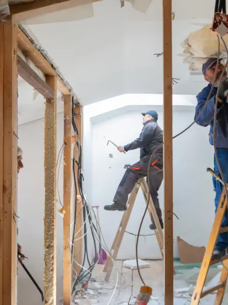 Drei Handwerker renovieren ein Zimmer.