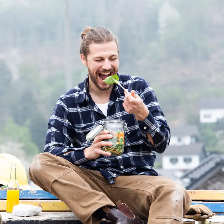Handwerker macht Pause und isst einen gesunden Salat.