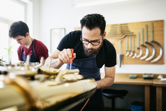 Ein Handwerker nutzt einen Schraubenzieher bei der Arbeit in der Werkstatt.