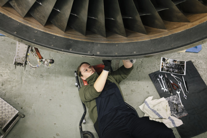 Handwerkerin liegt unter einer Turbine zur Reperatur.